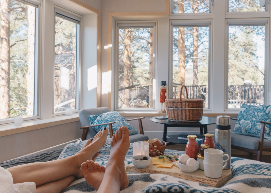 Två personer som ligger på en säng med en bricka med frukost inne i ett Fågelnäste.