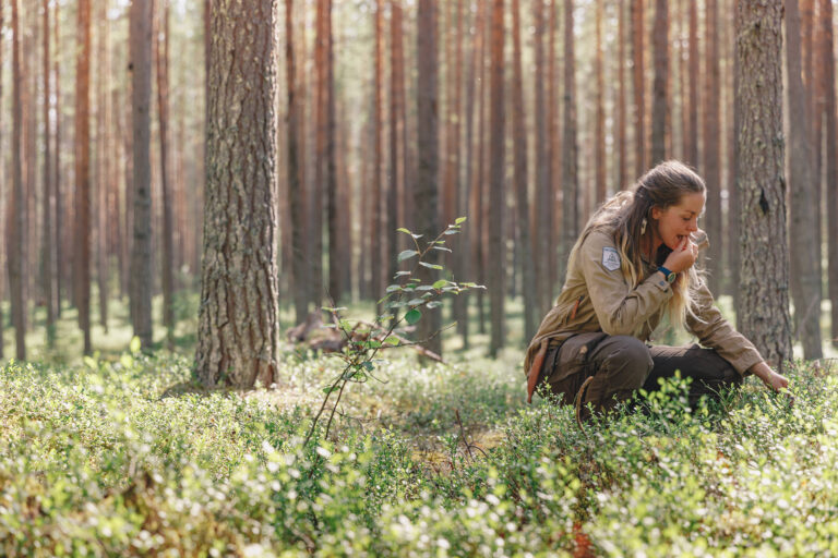 Kvinna smakar på bär i skogen