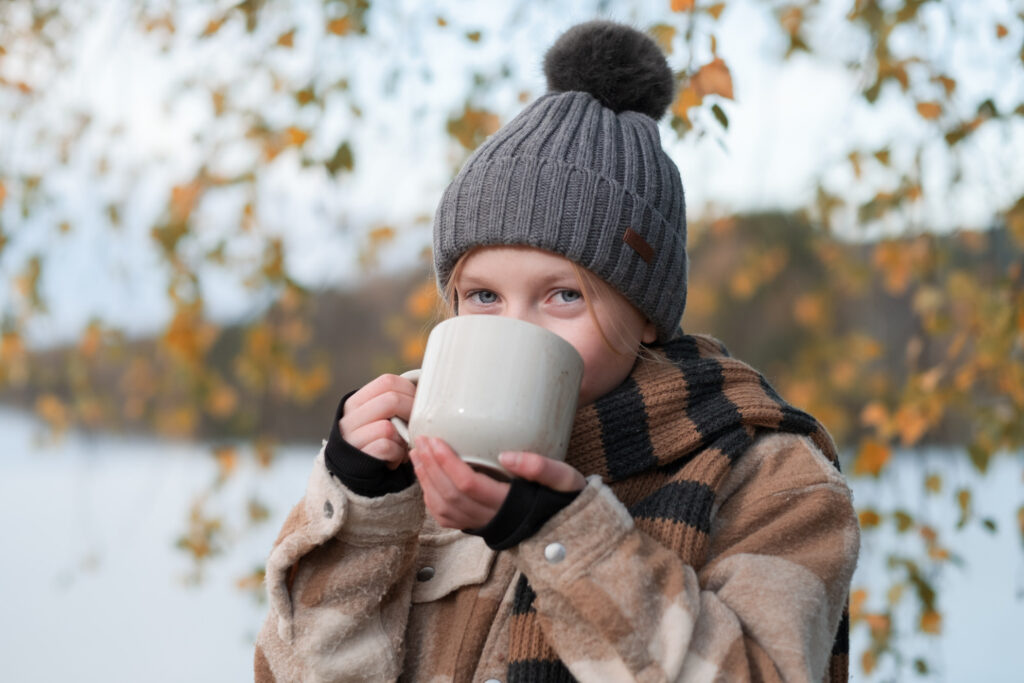 Flicka som dricker varmchoklad ur mugg utomhus