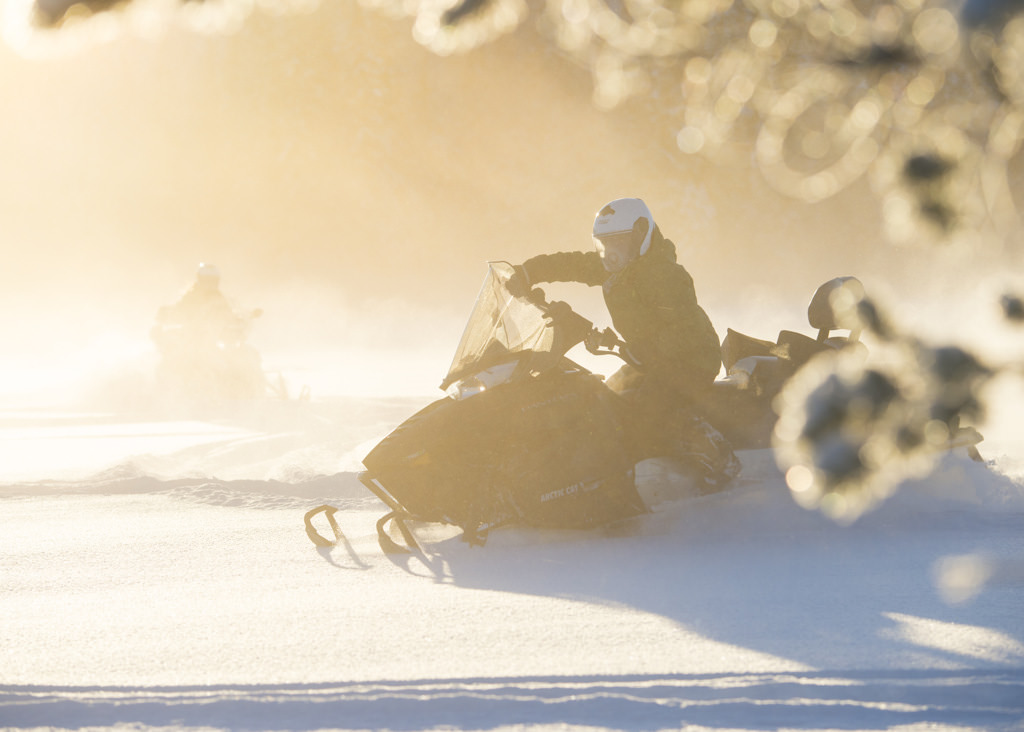 Kvinna kör skoter i virvlande snö