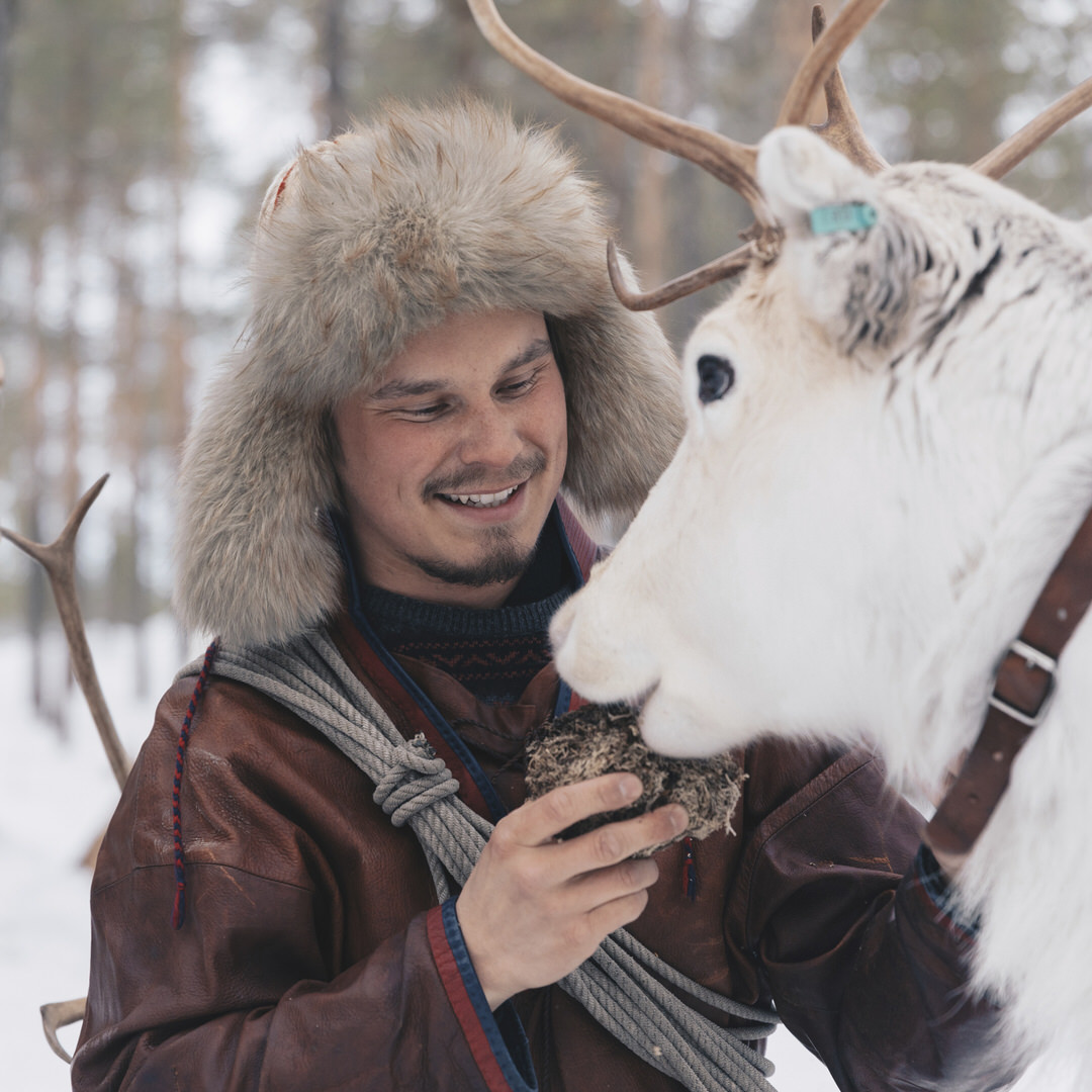 A man standing next to a reindeer.