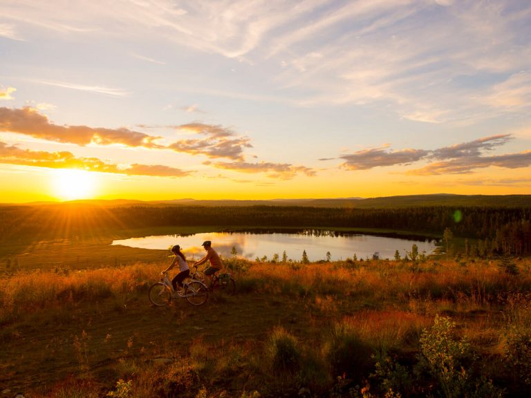 Par som cyklar i solnedgång vid en sjö