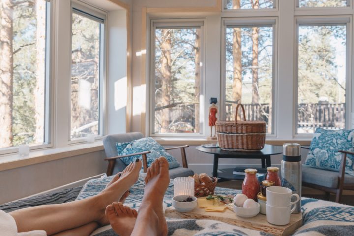 Två personer som ligger på en säng med en bricka med frukost inne i ett Fågelnäste.