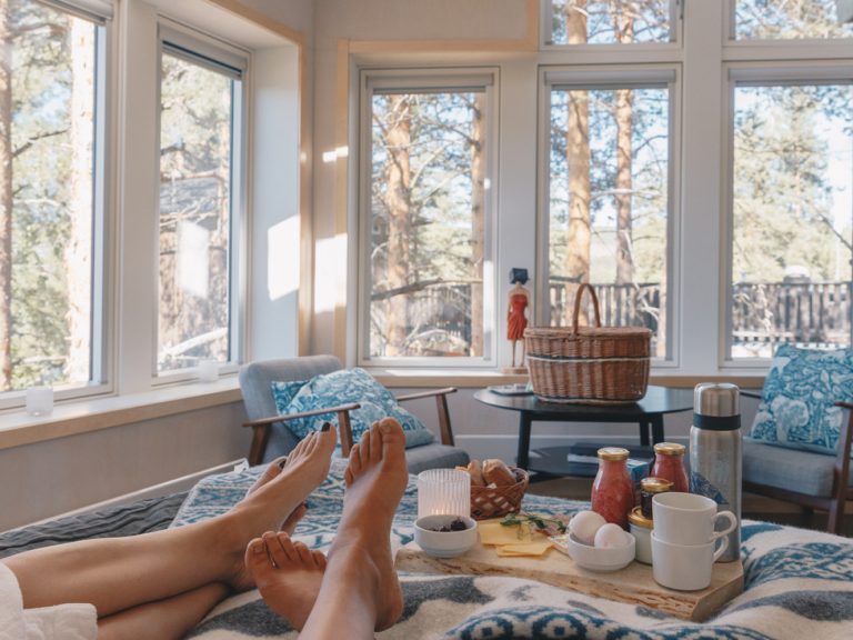 Två personer som ligger på en säng med en bricka med frukost inne i ett Fågelnäste.
