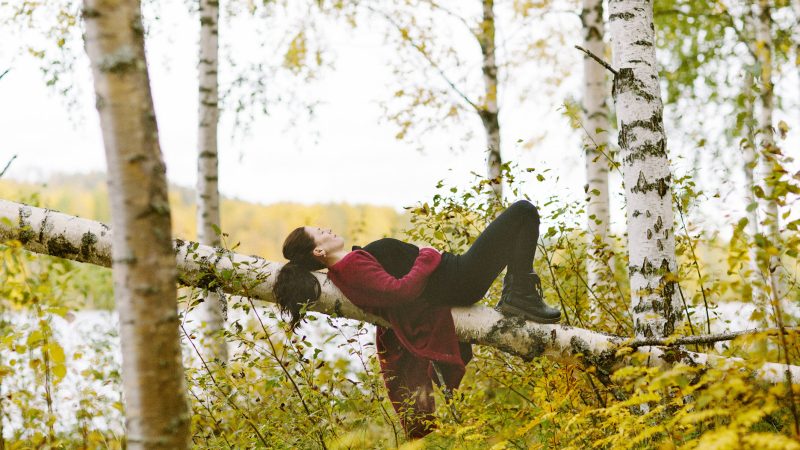 Yoga - kvinna ligger och vilar på en björk